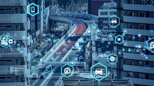 Dense urban traffic landscape overlaid with futuristic digital graphics to indicate connectivity and data exchange between vehicles and infrastructure.  