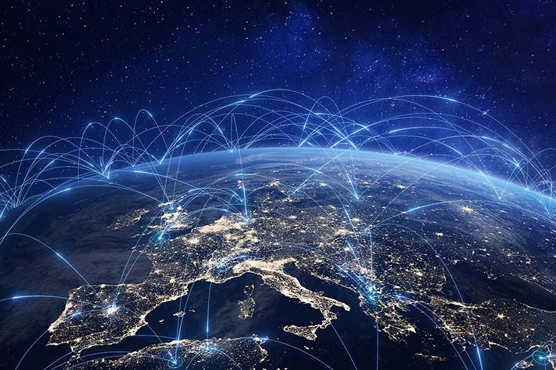 Wireless communication networks visualized as light bands arcing from city to city across a satellite image of Europe at night