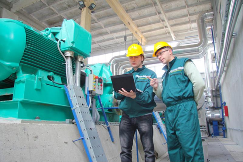 Two factory workers inspect machinery 