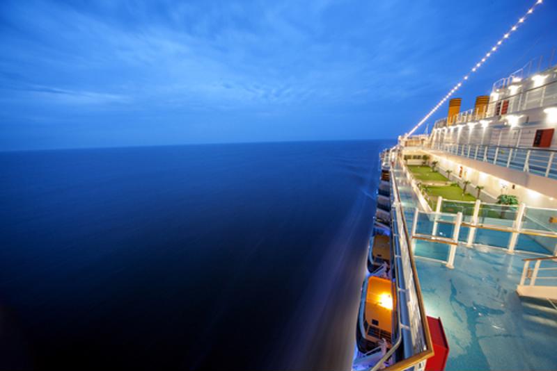 Top deck view of the side of a  cruise ship at sea.