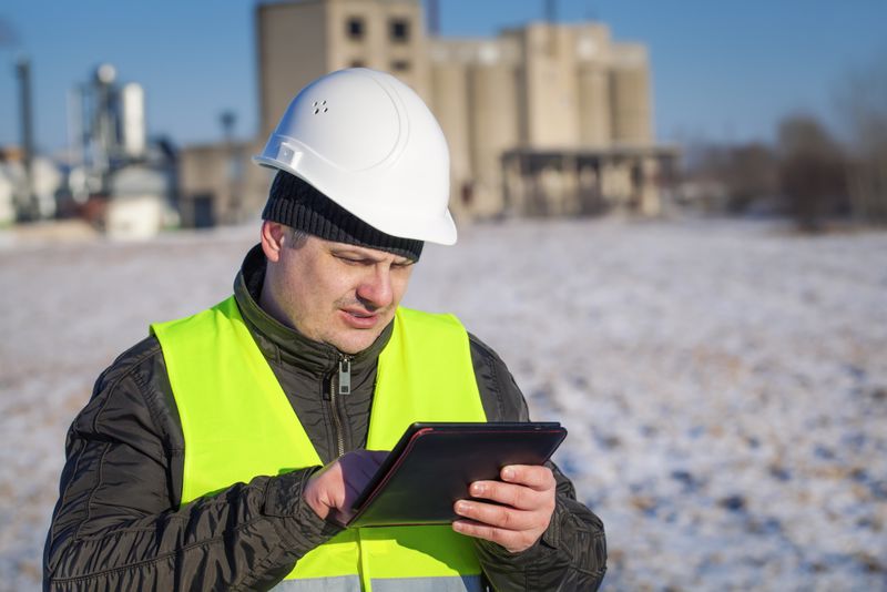 Factory worker standing in snow with digital tablet