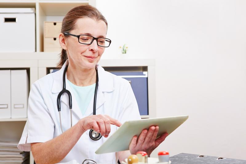 Female doctor looking over patient information on a tablet.