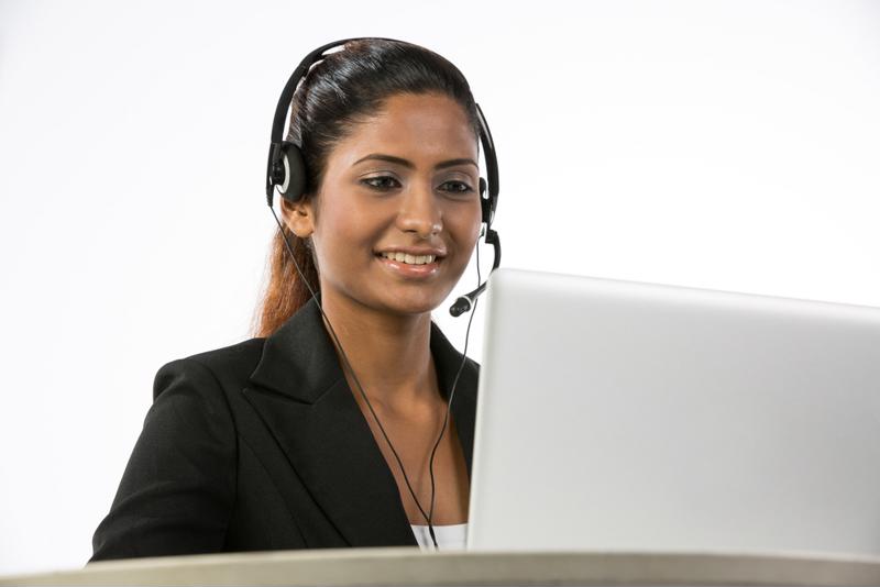 Indian woman smiling while she handles a customer call.