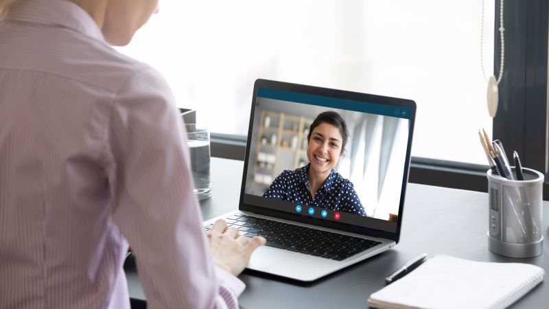 A patient on the computer screen chats with her doctor who is seated in her own office.